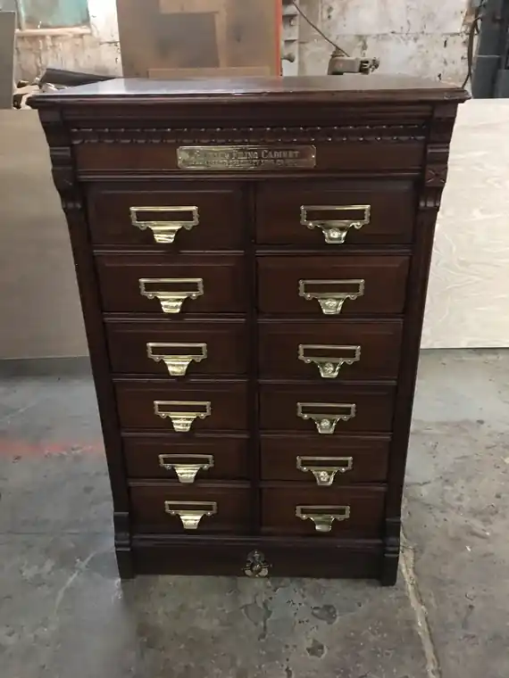 Tall oak file cabinet with rows of brass card pulls