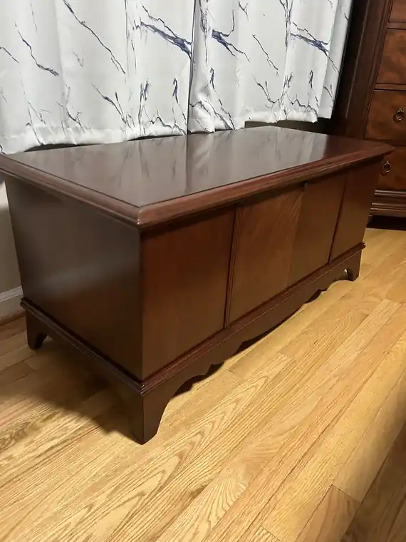 Cherry cedar chest with a glossy refinished top and plain front panels, on a hardwood floor