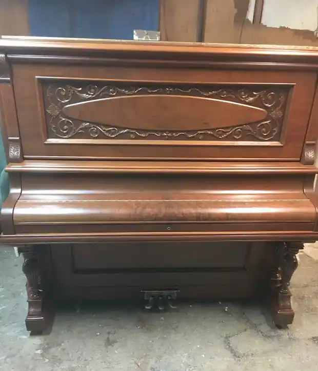 Upright piano case with a carved front panel
