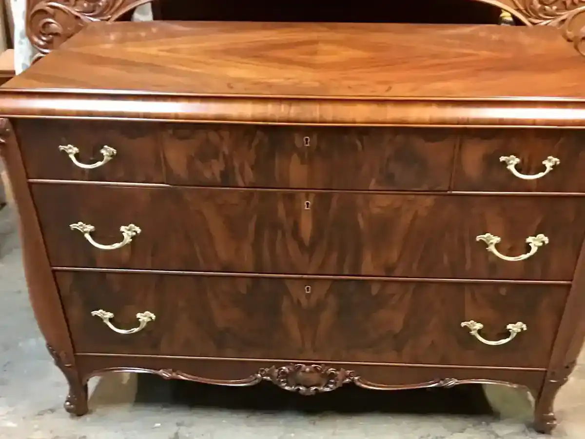 Serpentine chest of drawers in flame mahogany with a diamond-matched top, brass bail pulls and a carved apron
