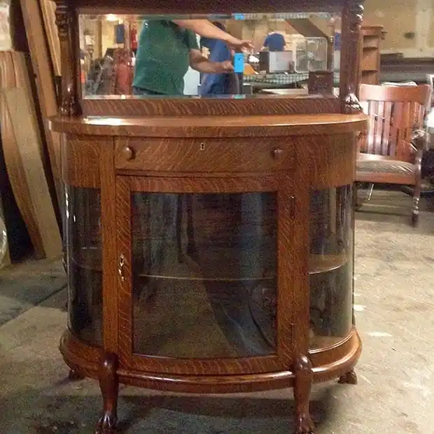 Oak china cabinet with a curved glass front and a mirrored top