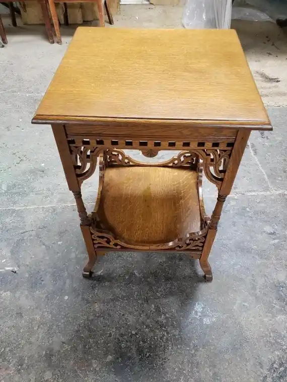 An oak parlor stand with a fretwork apron, turned legs and a curved lower shelf