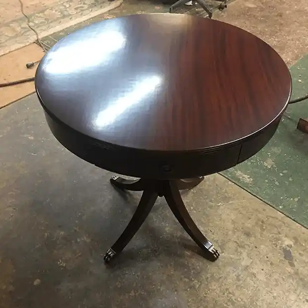 Round dark mahogany pedestal table on splayed legs with brass caps