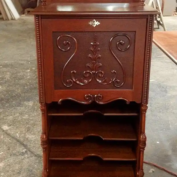 Drop-front secretary desk with a carved panel and open shelves below