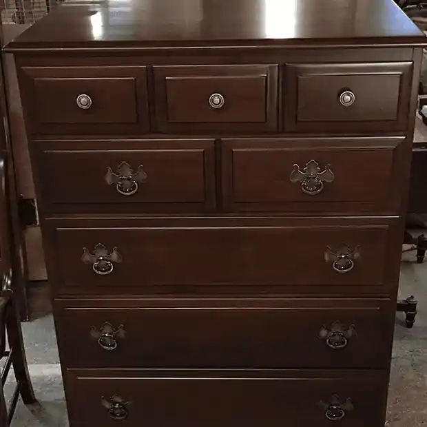 Tall dark walnut chest of drawers with round brass-toned pulls